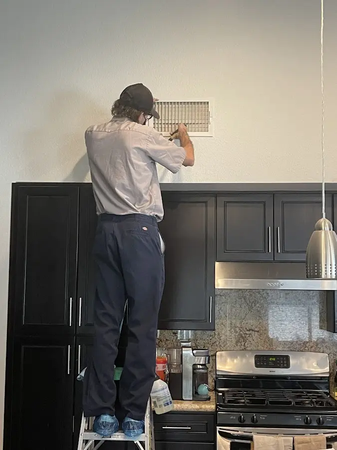 Technician inspecting an air vent during HVAC service in Murrieta